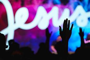 shadows of peoples hands with the Name Jesus in white letters